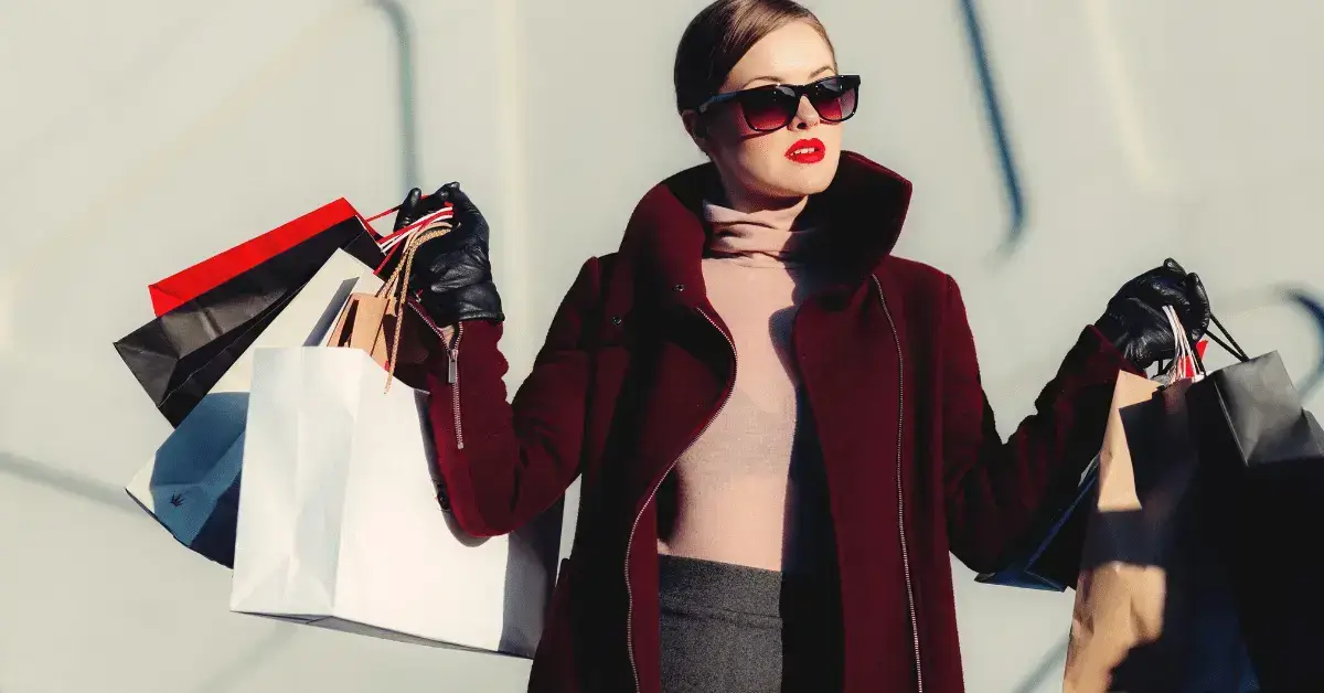 A woman wearing sunglasses walking with shopping bags