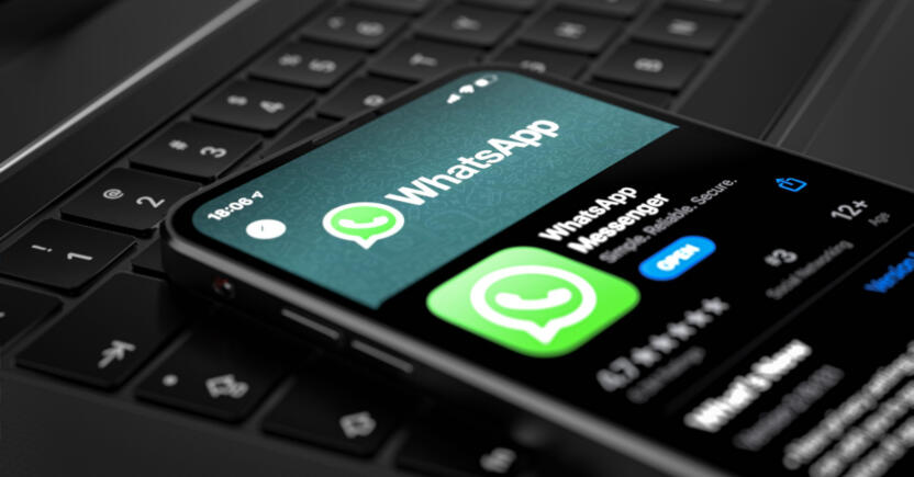 A mobile device with the WhatsApp messenger app open, resting on a laptop keyboard